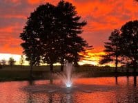 Olympus Fountain with Artemis Nozzle in a pond during a vibrant sunset.