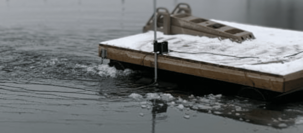 Pond Perfections Blog Feature Image - Pond Perfections Dock-mounted Kasco AquaTiClear Circulator preventing ice formation in a snowy environment.